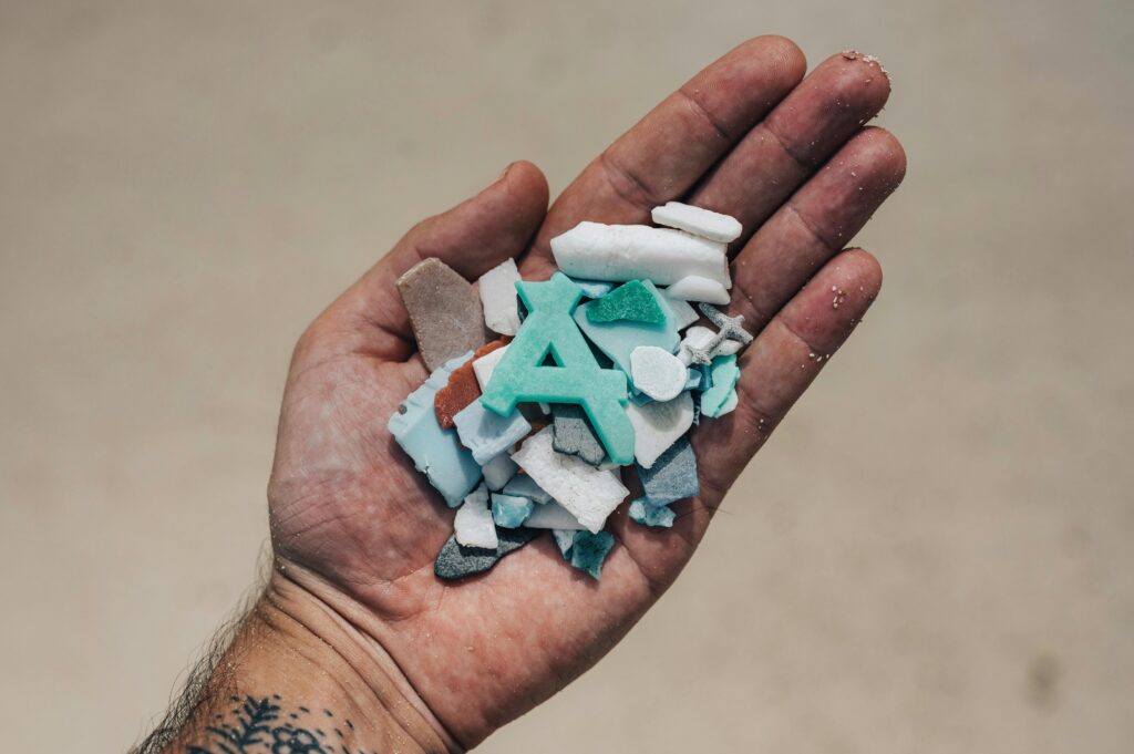 Hand holding assorted pieces of beach plastic debris highlighting environmental impact.