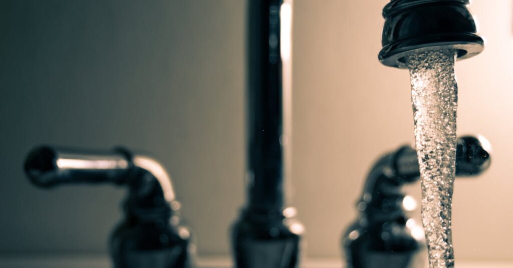 A detailed shot of water flowing from a steel faucet, ideal for themes on cleanliness or plumbing. Microplastics in water
