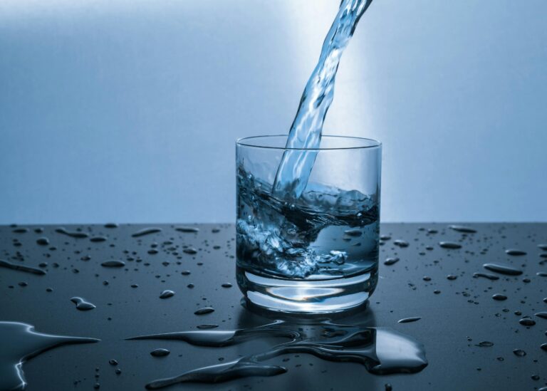 Clear water being poured into a glass on a kitchen counter in natural light