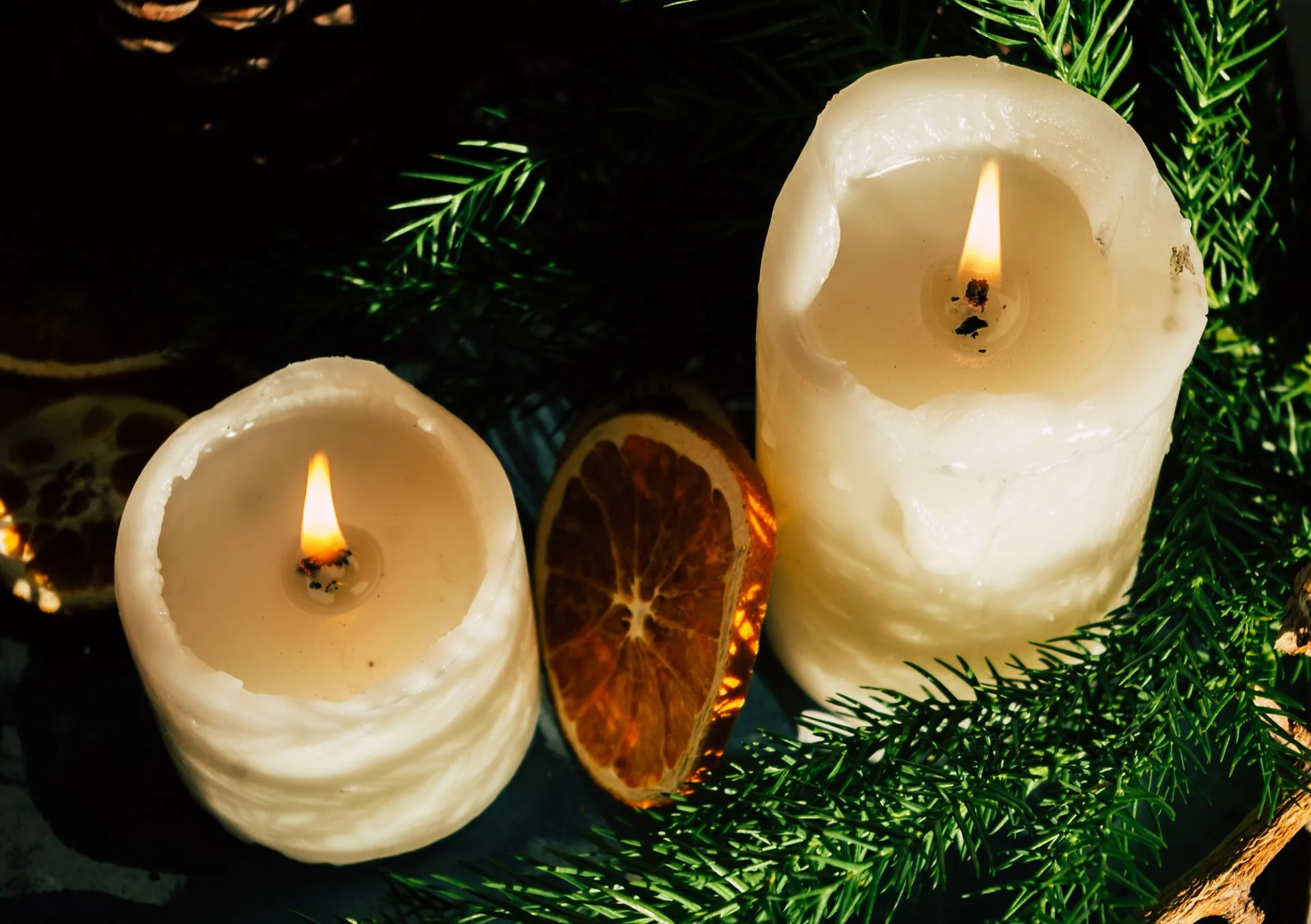 Cozy Christmas bedroom with natural linen bedding, a wool throw, lit beeswax candles and an amber glass dispenser on the nightstand