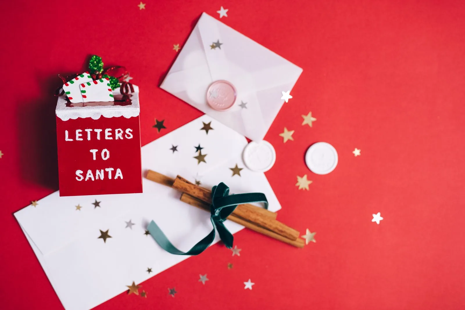 Christmas letters and envelopes with festive decorations on a red tabletop