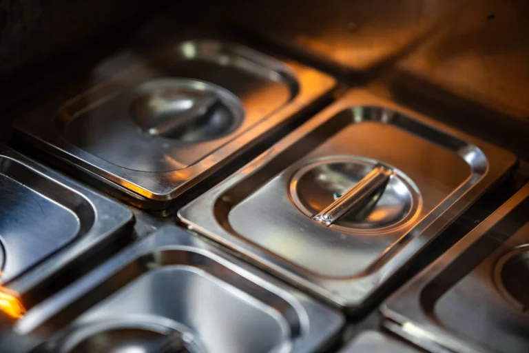 Stacked stainless steel food containers with lids in warm kitchen light