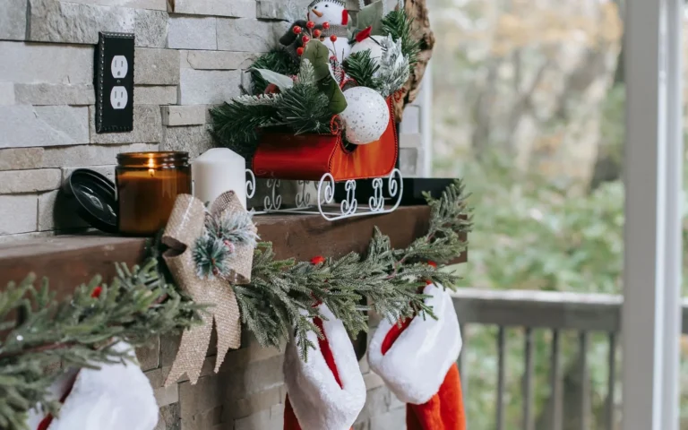 Red Christmas stockings and fresh fir greenery decorating a mantel above a brick fireplace